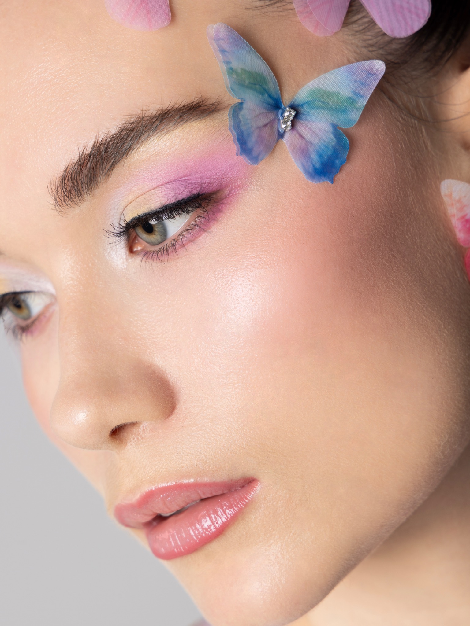 Macro beauty detail of pink and lilac blended eye shadow with a fine liner and dewy skin.