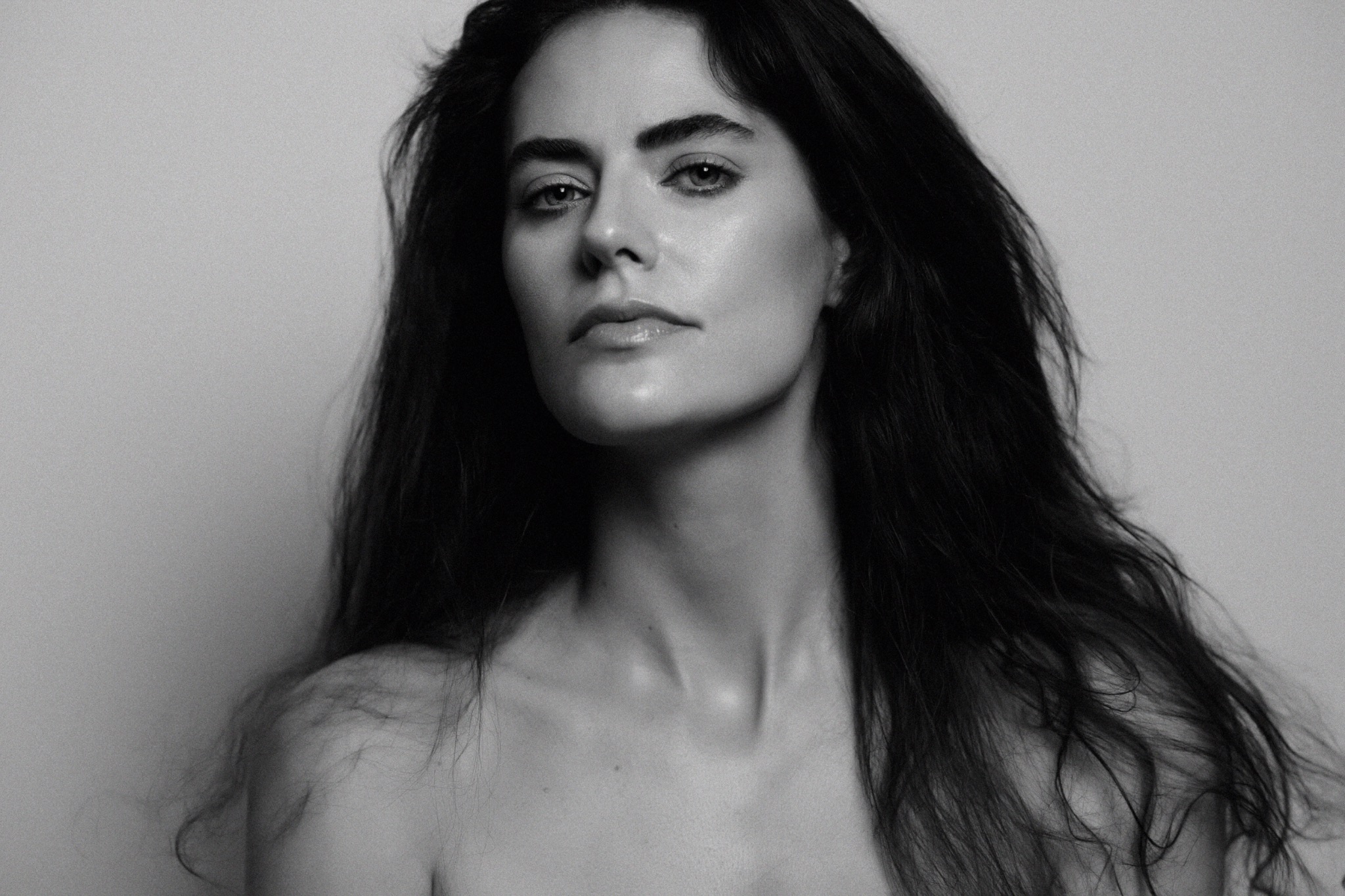 Black and white beauty portrait turned slightly aside, with luminous skin, sculpted highlights and a soft glossy lip.